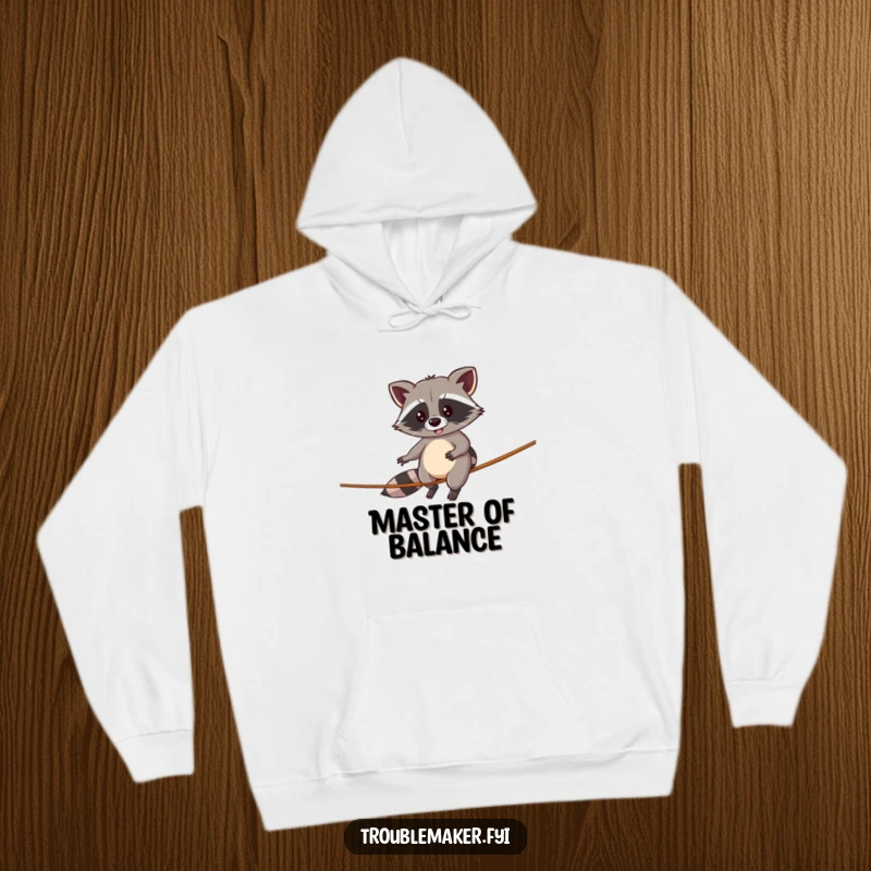 Funny hoodie featuring a determined raccoon precariously walking a tightrope, offering warmth and humorous encouragement.