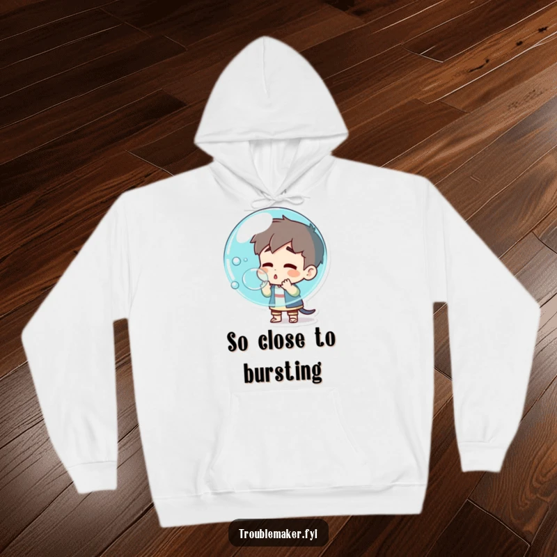 Funny troublemaker character blowing a giant bubble that's about to pop, depicted on a cozy hoodie, representing explosive fun and anticipation.
